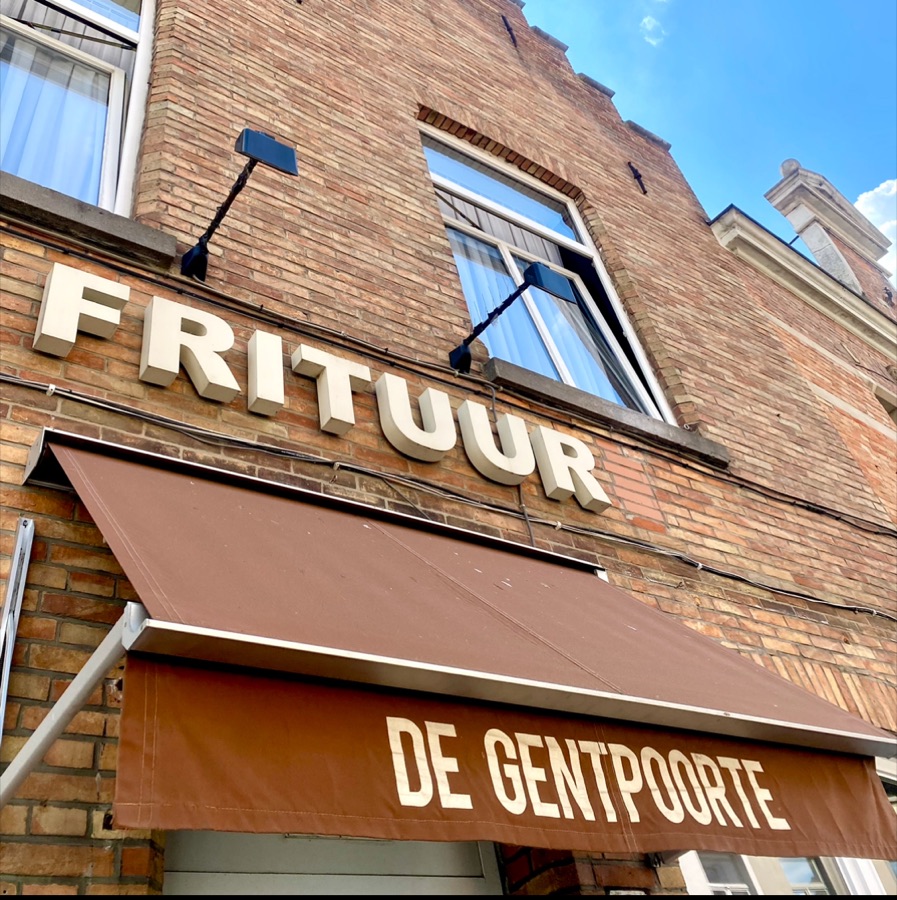 De gevel van Frituur De Gentpoorte in de Gentpoortstraat, met het FRITUUR-uithangbord en de bruine luifel.
